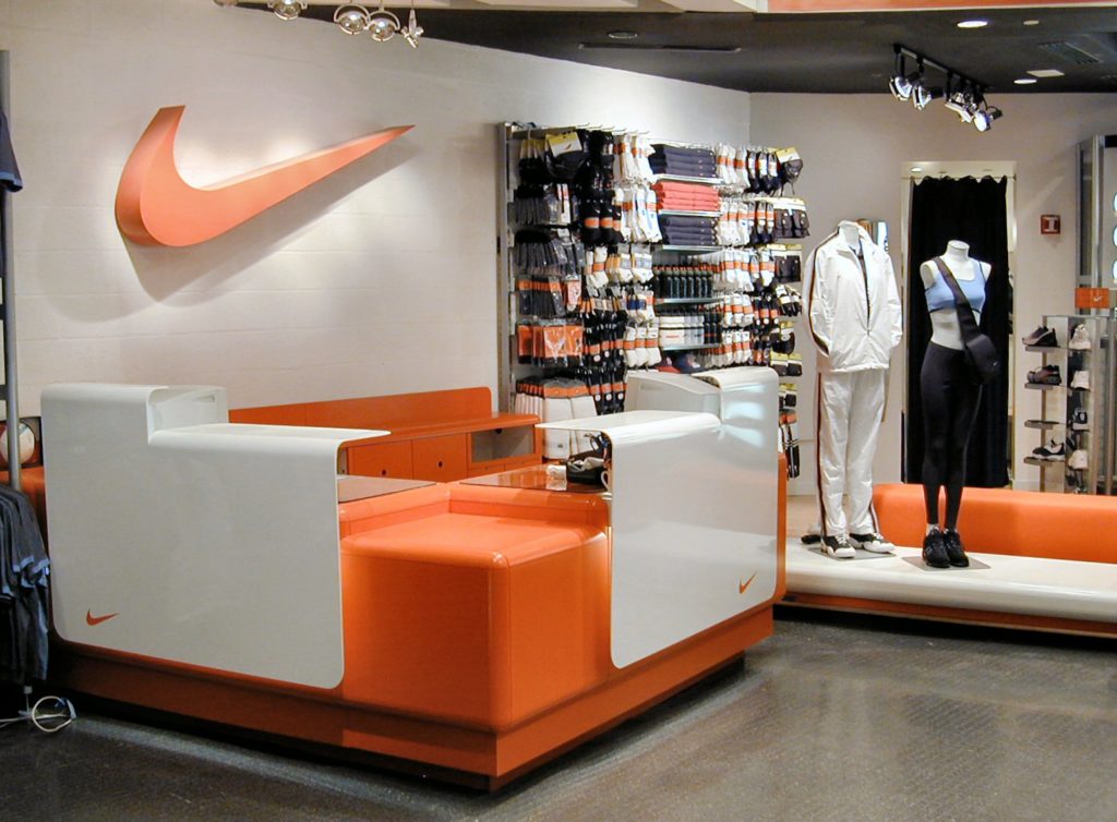 A nike store interior with white and orange custom fabricated sales desk.