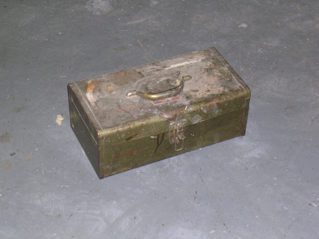 A simple metal toolbox sitting on a floor.